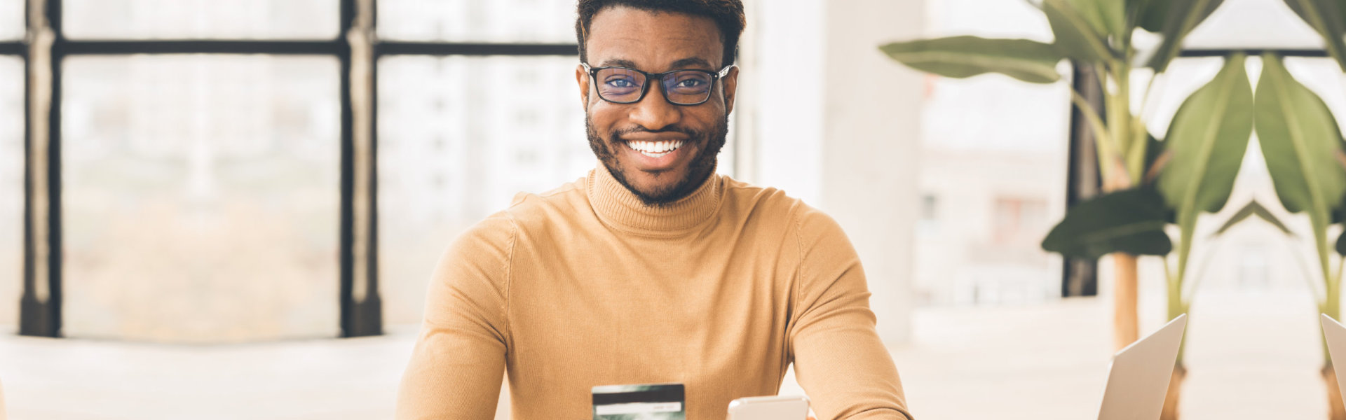 Online Store. Millennial guy holding credit card and smartphone, ready to buy something. Free space