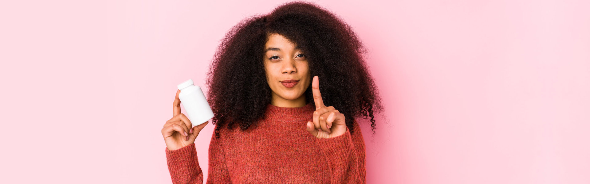 Young woman holding a vitamins isolated Young woman holding a vitamins showing number one with finger.